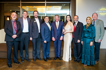 Nine individuals in formal dress attire pose for the camera.