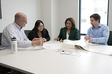 Four people sit around a table looking at planning documents.