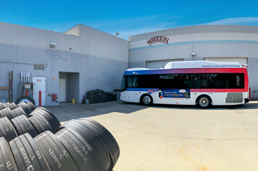 An exterior view of a municipal bus maintenance garage. A hydrogen-fueled bus is in front of two garage doors.