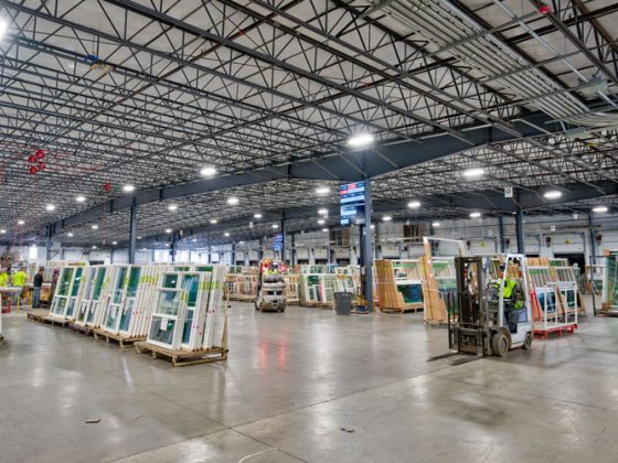 Exposed metal ceiling trusses over newly manufactured windows on the floor of a window production facility.