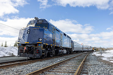 A blue train on tracks heading into the frame.