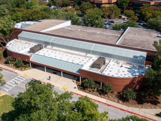 Aerial view of the Arundel Olympic Swim Center. Half of the roof is a white reflective membrane. The other half has a sloped gravel covering. Trees surround the building.