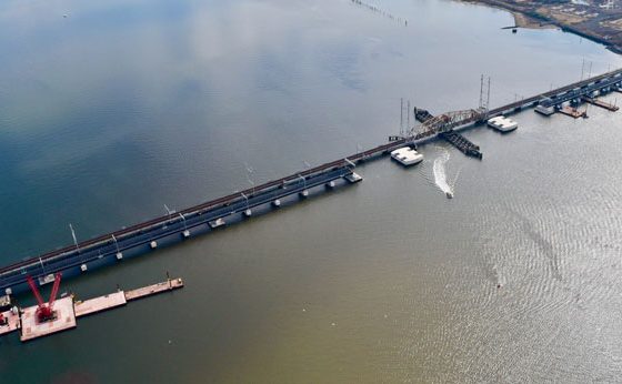 Arial image of two bridges crossing a river with a boat crossing underneath.