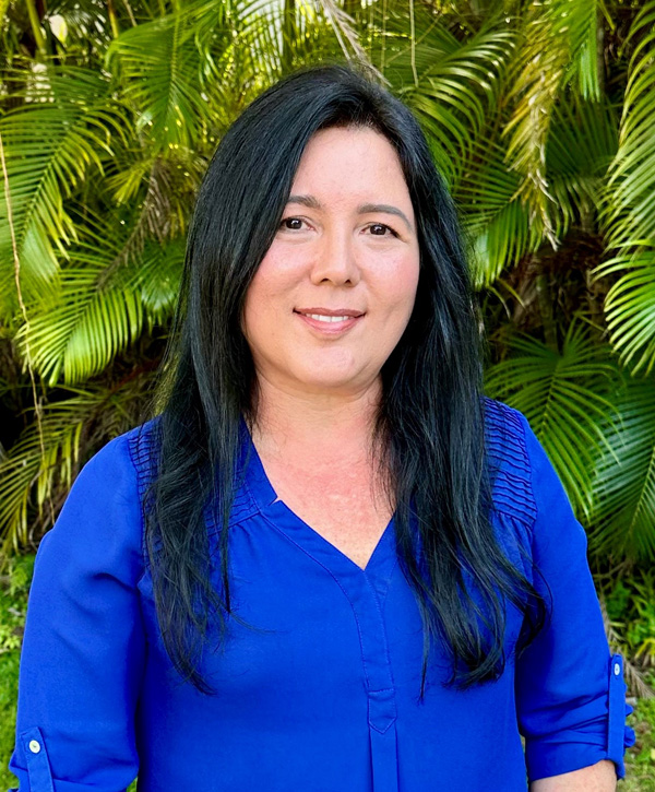 A woman with dark hair wearing a blue shirt smiling for the camera.