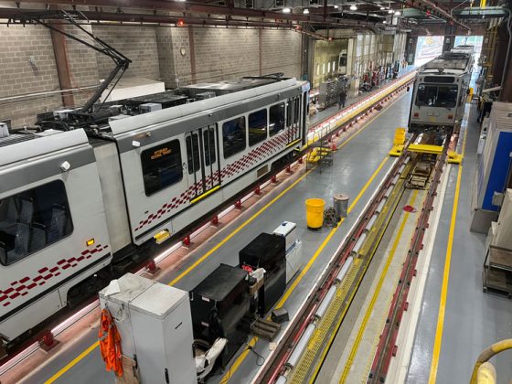 The interior of a rail maintenance facility featuring two parallel tracks with light rail vehicles on each.