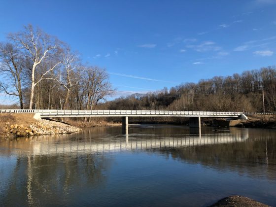 A steel beam bridge over the Licking River on a clear day.