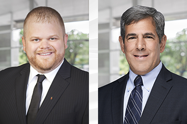 Two men wearing dark suits and ties.